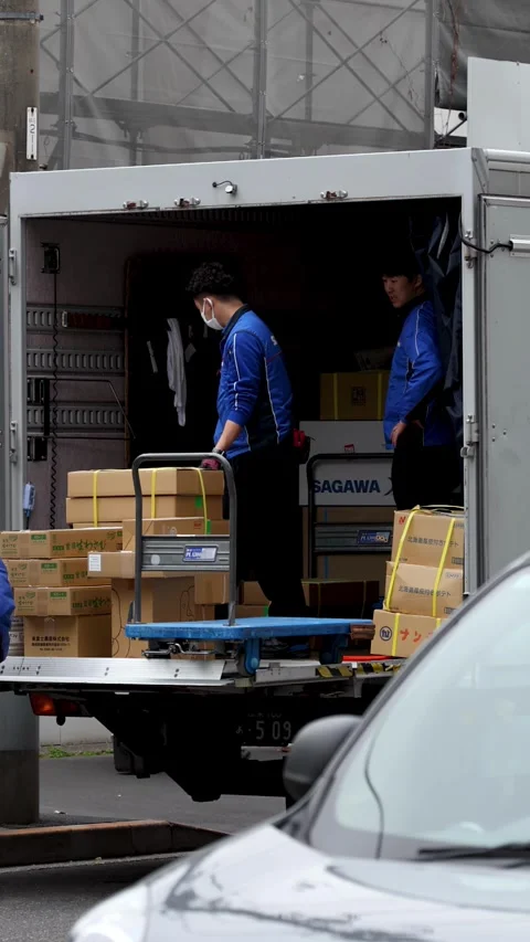 Japanese Delivery Workers Loading Cardboard Boxes into a Logistics Truck Stock Footage 343594489