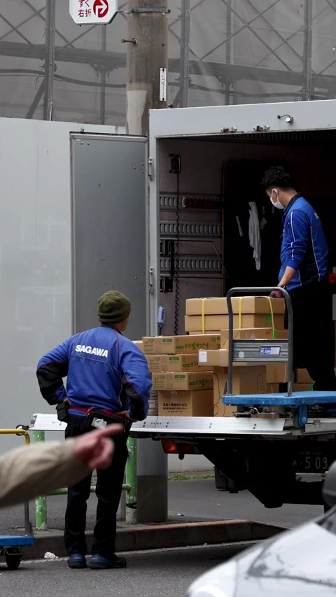 Japanese Delivery Workers Loading Cardboard Boxes into a Logistics Truck Stock Footage 343836638