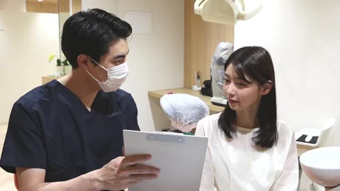 Japanese Dentist Explaining Treatment Plan to Female Patient with Clipboard Stock-Footage 343906711