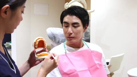 Japanese Dentist Teaching Proper Tooth Brushing with Dental Model 스톡 동영상 343906987