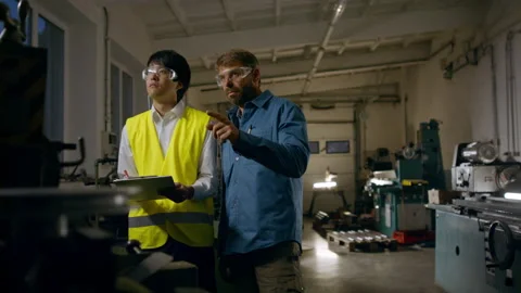 Japanese engineer controlling mature worker indoors in metal workshop. Stock Footage 165071386