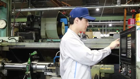 Japanese Factory Worker Operating CNC Lathe with Control Panel 動画素材 344065818