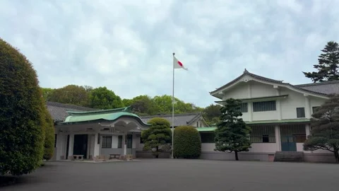 The Japanese flag waves on a flagpole outside the Meiji Jingu shrine office. Stock Footage 334579782