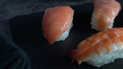 Japanese food composition. Various types of sushi, salmon placed on a black s Stock Footage 136511706