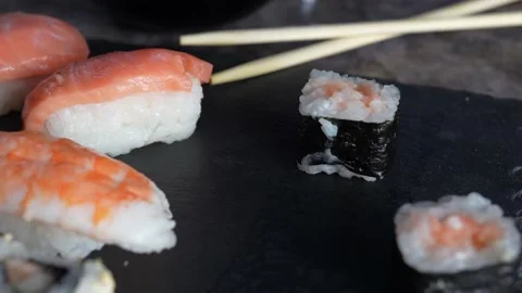 Japanese food composition. Various types of sushi, salmon placed on a black s Stock Footage 136511740