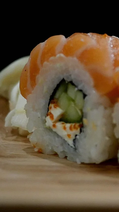 Japanese food. Grab salmon sushi roll with chopsticks from wooden board and lift Stock Footage