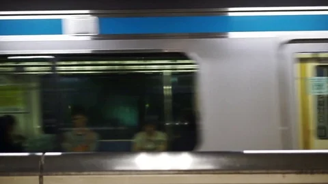 Japanese guy walking in reverse direction with running metro train Stock Footage 71583056