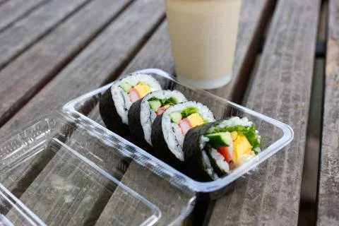 Japanese maki rolls with tuna, crabsticks, egg and greens in plastic lunch bo Stock Photos