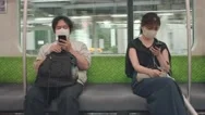 Japanese Man And Woman Wearing Masks And Using Their Smartphones Inside A Stock Footage