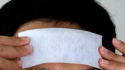 Japanese man applying a cooling sheet to his forehead Stock Footage 327885140