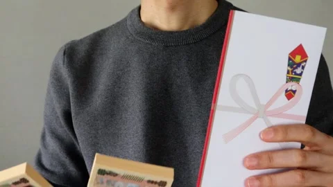 Japanese man holding a gift envelope and a stack of bills Stock Footage 324548792
