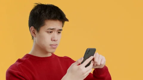 Japanese Man Using Phone Scrolling And Nodding Head, Yellow Background Vidéo 157719062