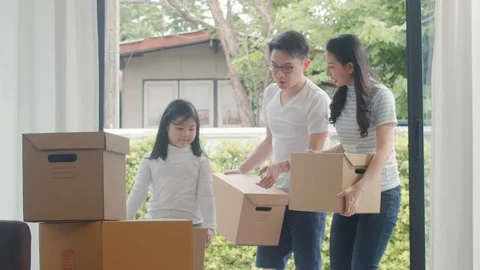 Japanese Mom, Dad, and child smiling happy hold cardboard boxes for move. Stock Footage 116841953
