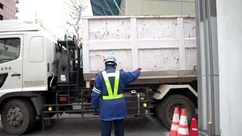 Japanese Security Guard Directing a Large White Dump Truck in Tokyo Stock Footage 334698063