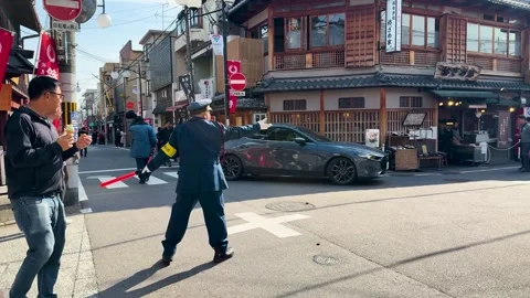 Japanese Security Guard Directing Traffic at a Busy Kyoto Street Intersection Stock Footage 332319867