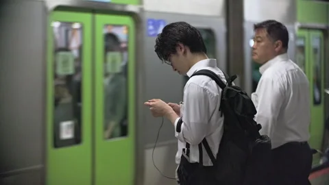 Japanese using smartphone while waiting for train at train station. Information  動画素材 244053990