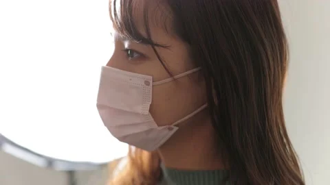 Japanese young beautiful model put face mask on in front of light. Slow-mo Stock Footage 221021054