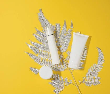 Jar and empty white plastic tubes for cosmetics on a yellow background. Pa... Stock Photos