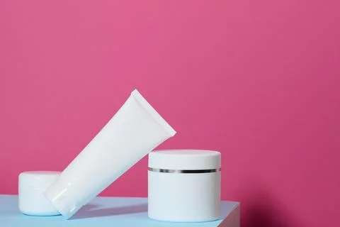 Jar and empty white plastic tubes for cosmetics on a pink background. Packa.. Stock Photos