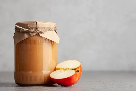 Jar of apple jam with half an apple on gray background Stock Photos