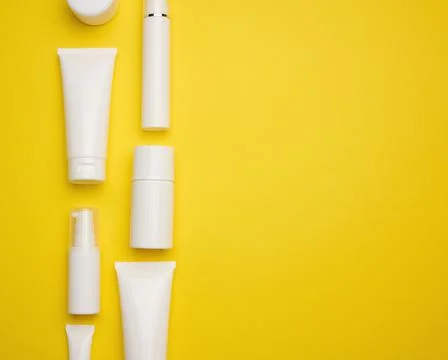 Jar, bottle and empty white plastic tubes for cosmetics on a yellow backgroun Stock Photos