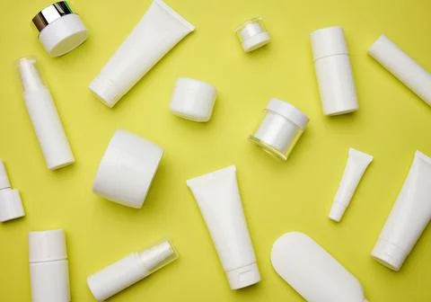 Jar, bottle and empty white plastic tubes for cosmetics on a yellow backgroun Stock Photos