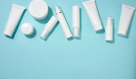 Jar, bottle and empty white plastic tubes for cosmetics on a blue background. Stock Photos