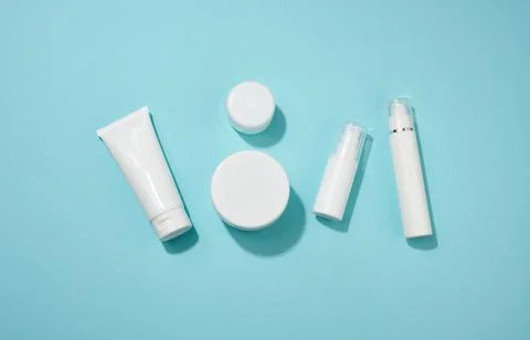 Jar, bottle and empty white plastic tubes for cosmetics on a blue background. Stock Photos