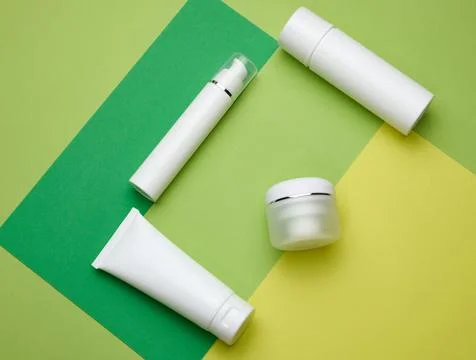 Jar, bottle and empty white plastic tubes for cosmetics on a green background Stock Photos