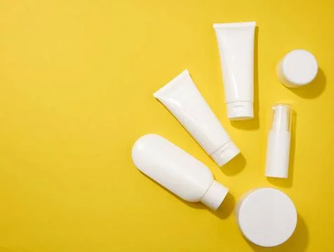 Jar, bottle and empty white plastic tubes for cosmetics on a yellow backgr... Stock Photos