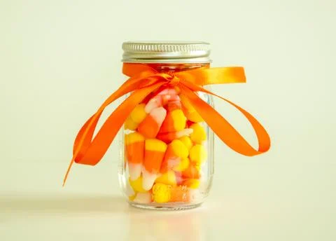 Jar of candy corn tied with orange ribbon Stock Photos