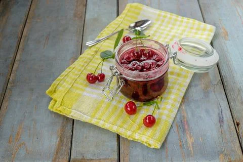 Jar of cherry jam and some cherries on the napkin Stock Photos
