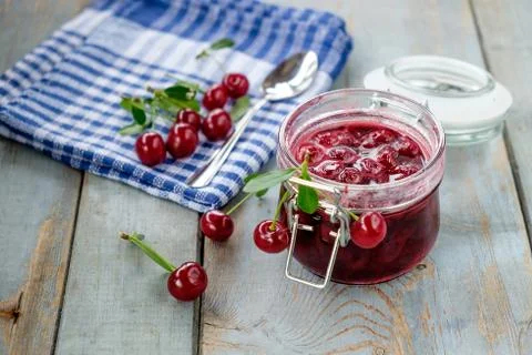 Jar of cherry jam and some cherries on the napkin Stock Photos