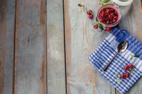 Jar of cherry jam and some cherries on the napkin Stock Photos