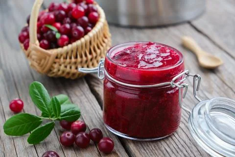 Jar of crushed cranberries for sauce or jam and basket of bog berries. Stock Photos