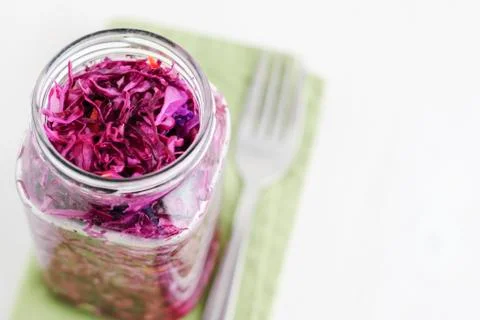 Jar with fermented cabbage and fork on napkin Stock Photos
