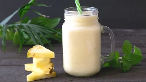 Jar with freshly squeezed pineapple smoothie on a wooden table. Stock Footage 235060832
