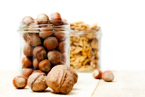Jar of hazelnuts, with jar of walnuts in the background Stock Photos
