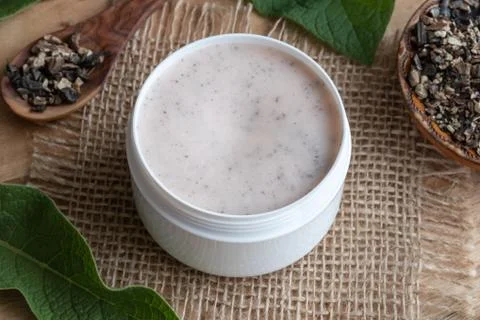 A jar of homemade comfrey root ointment with fresh symphytum plant Stock Photos