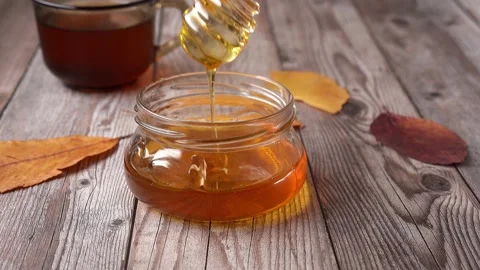 A jar of honey with dipper on rustic table Stock Footage 138382212