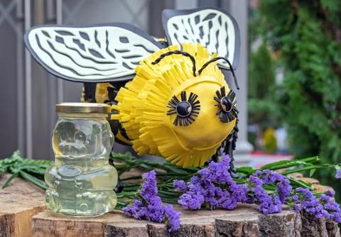 Jar of honey in the shape of a bear on the background of a large bee. Stock Photos