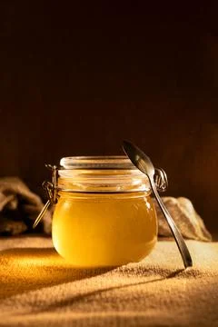 Jar of honey with spoon on rustic background with copy space. Stock Photos