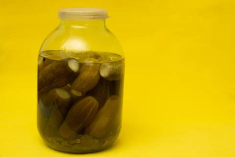 A jar of pickles, on a yellow background Stock Photos