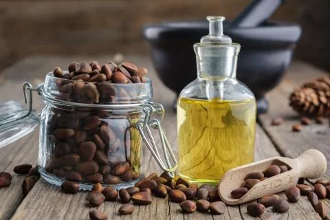 Jar of pine nuts and pine nuts essential oil bottle. Mortar on background. Stock Photos