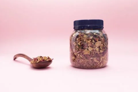 Jar, plastic container with dried rose petals, leaves. Wooden spoon filled with Stock Photos