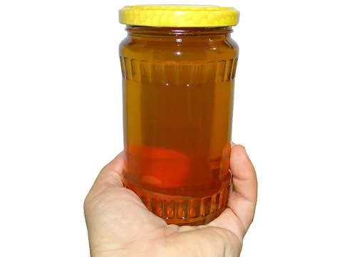 Jar of polyflora honey in one hand Фото