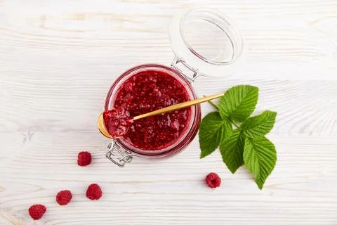 Jar of raspberry jam and fresh berries on light background. Stock Photos