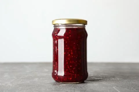 Jar of raspberry jam on grey table Stock Photos