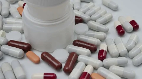 Jar with red, white, brown, orange pills rotating Stock Footage 81260221