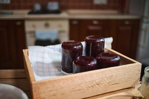 Jars with berry jam stacking upside down on wooden crate, standing on kitchen Stock Photos